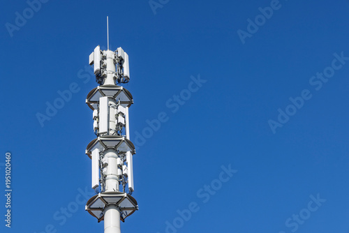 Telecommunication tower cell site with multiple mobile network antennas and transmitters for 5G and 4G in the future 6G signal coverage against clear blue sky.