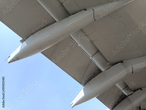 Close-up photo of an aircraft wing taken from below with the canoe fairing and slats under bright blue sky