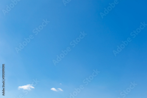 Small white clouds at the bottom of a vast clear blue sky