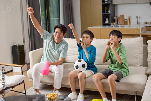 Boys and their dad watching a football game at home