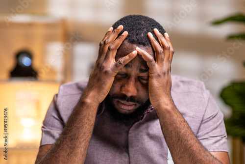 Obraz na płótnie African man closing eyes, holding head in pain, feeling frustrated and stressed