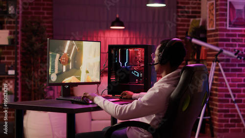 Foto Static tripod shot of african american gamer streaming first person shooter while explaining gameplay while using pc gaming setup