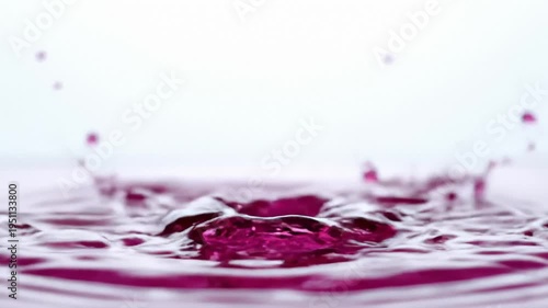 Close-Up of Magenta Liquid Droplets Falling Into Water Creating Ripples and Splashes