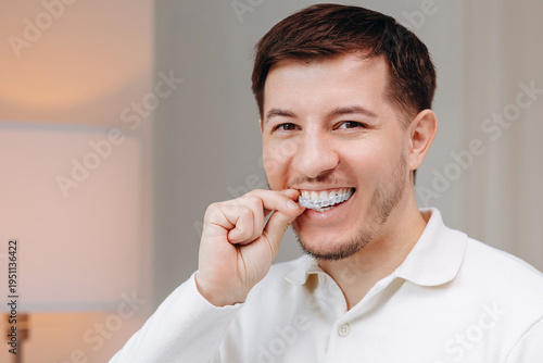 Man placing clear aligner for teeth while smiling to show oral care and orthodontic treatment