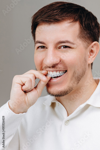 Young man inserting clear aligner tray for teeth, dental care and confident smile at home