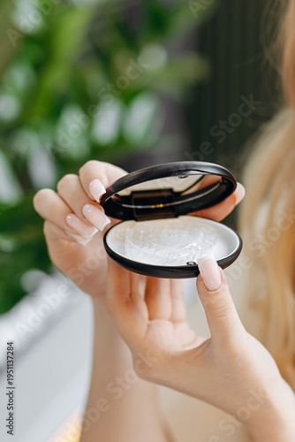 Woman holding clear dental aligner in a compact case before inserting invisible retainer