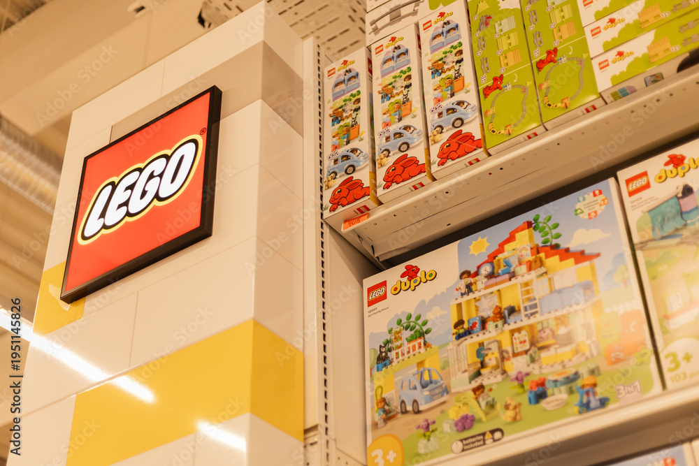 Fototapeta premium Chemnitz, Germany - March 14, 2026: Shelves feature various Lego toy sets for sale in a retail store. The Lego logo is visible, indicating the brand. Shoppers browse the colorful selections
