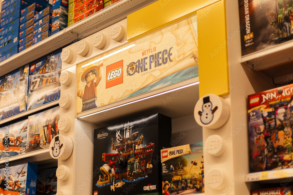 Naklejka premium Chemnitz, Germany - March 14, 2026: Shelves show Lego sets featuring One Piece branding. Customers browse through various options for creative play. Scene set in a busy retail store filled with toys