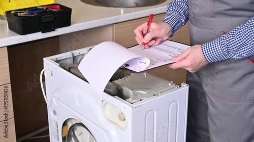 A close-up of a service engineer writing an invoice for washing machine repair.