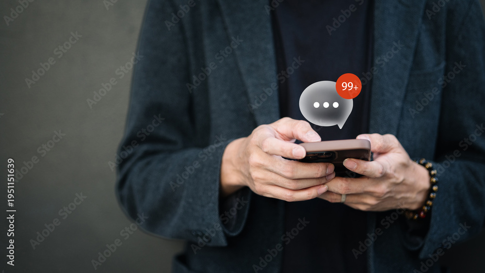 Fototapeta premium Person using smartphone with 99 plus message notification bubble icon for digital communication concept.