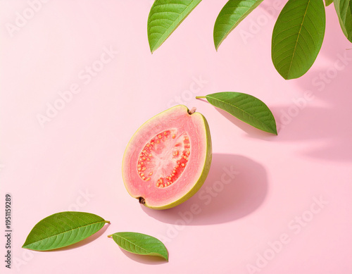 A single slice of ripe pink guava sits center-stage on a soft pink surface, framed by fresh green leaves and gentle shadows for a clean, tropical, and minimalist look.