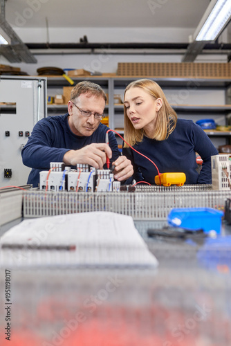 Two electricians working on circuitry in workshop