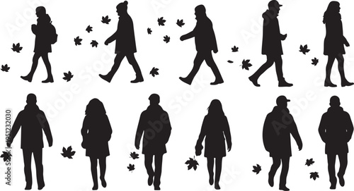 Silhouettes of people walking with autumn leaves falling around