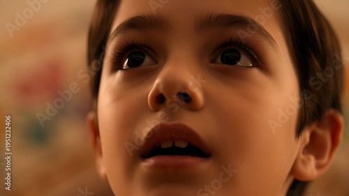 Close-up video footage of a young boy looking up in wonder and excitement