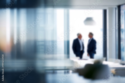 Blurred Two businessmen in conversation at modern office with large windows