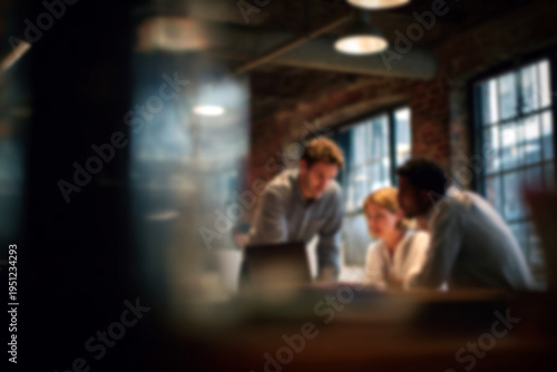 Blurred Diverse team collaborating on laptop in modern office space