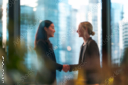 Blurred Two professional businesswomen shaking hands in modern office