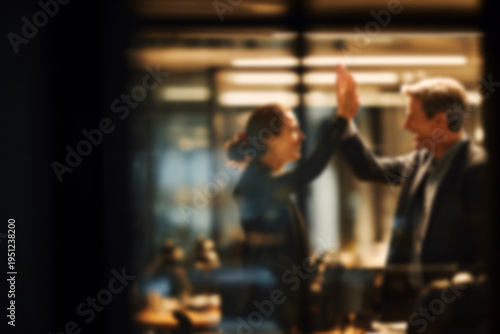 Blurred Business colleagues celebrating success with a high five in modern office