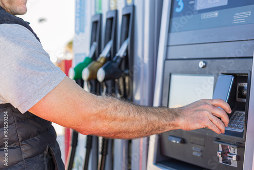 Man paying for fuel with smartphone at gas station