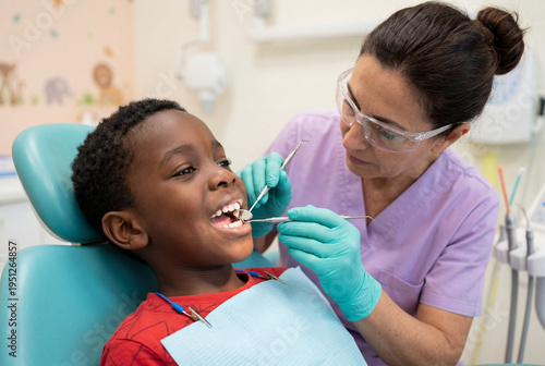Female dentist examining teeth of young black boy in clinic