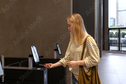 Quadro su tela Contactless check-in with smartphone at self-service access kiosk in modern office lobby, Gen Z hybrid work and smart building security concept, copy space