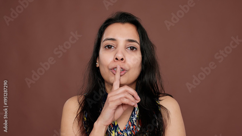 Tableau sur toile Secretive adult keeping secret with mute and silence sign, holding finger over mouth