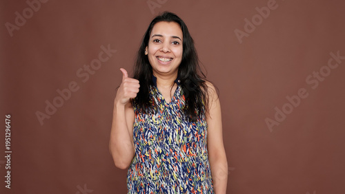 Fotografie Portrait of indian woman doing thumbs up gesture on camera, giving like and approval to idea