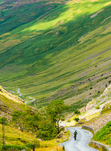 A bicycle rider peddles into Honister Pass,along a narrow,winding road,the Lake District,Cumbria,England,United Kingdom.