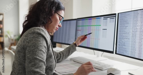 Woman analyst accountant in office reviewing spreadsheet. She checks data on a computer monitor to ensure accuracy and reporting for team leaders. Clear concept of financial data analysis.