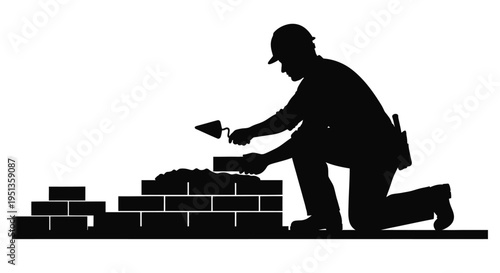 Construction worker laying bricks against a wall dramatic silhouette