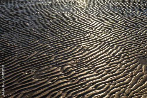 Фотография Rippled sand texture on beach created by sea waves at low tide