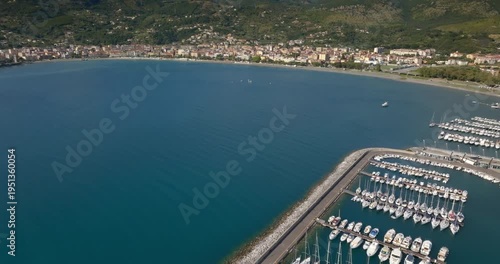 Panorama of the port of Sapri, located in the province of Salerno, Campania, Italy. In the background, the small town overlooking the bay. Aerial view of a sheltered harbor and its long breakwater.