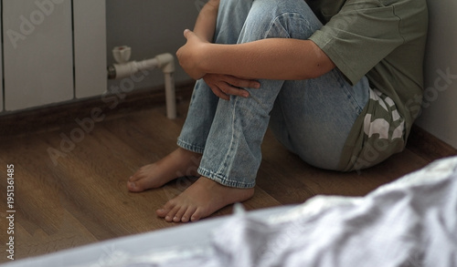 Photography the legs of a child sitting alone in the corner of a room
