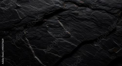 A high resolution close up view of the rough and dark textured surface of natural black slate rock