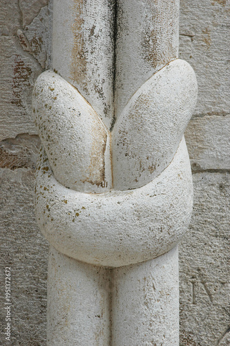 A macro shot of a unique decorative stone knot carved on a romanic pillar within an old mediterranean church or cathedral