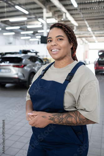 Картината върху платно Empowered young woman mechanic confidently working in a bustling auto repair sho