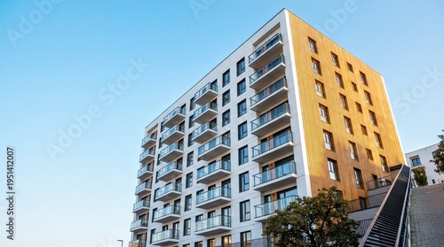 Modern residential building with glass balconies and wooden facade under a clear blue sky
