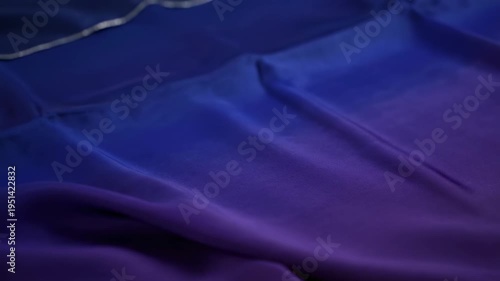 Soft and flowing, a silky fabric cascades with gradient from blue to purple