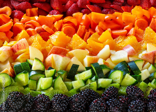 Rows of colorful fresh fruits and vegetables arranged by color in a gradient pattern.