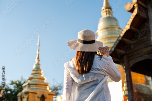 Young Asian woman solo traveling backpacker walking in temple at Chiang mai Thailand. Happy female tourist walking in the downtown street traditional ancient temple. Holiday vacation time tourist