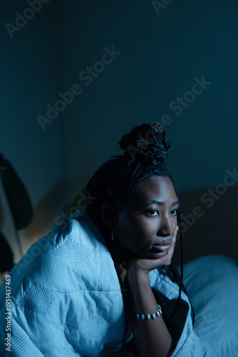 Person experiencing insomnia in dark bedroom, feeling worried