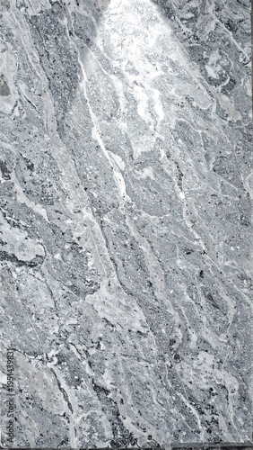 Gray stone slab with winding, white veining running diagonally across the surface, illuminated from above