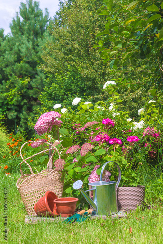 Summer leisure activities; watering can, flowerpots, tools on a blooming meadow near blooming plants
