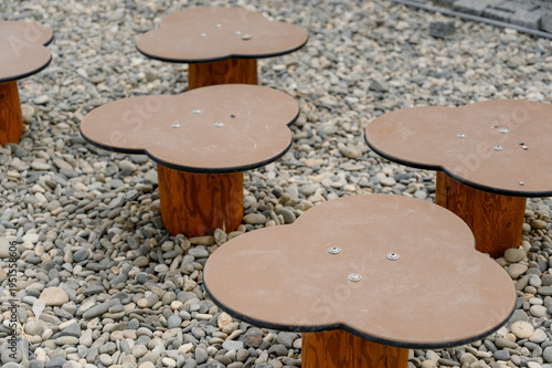 Unique flower-shaped tables on gravel surface in outdoor setting