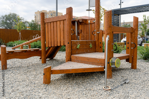 Wooden playground structure with climbing features and gravel surface