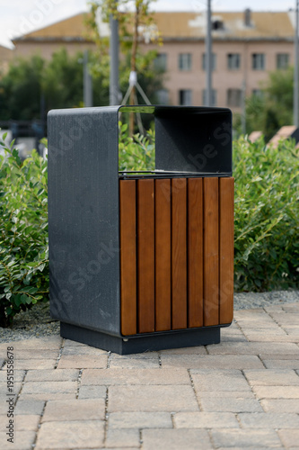 Modern outdoor trash bin with wooden slats in urban park setting