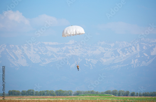Skydiving. Flying parachutists against the background of the blue sky and mountains. Extreme sport and entertainment.