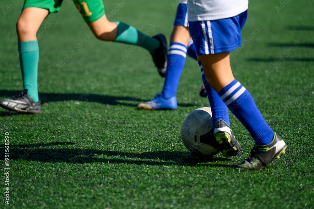 Fototapeta premium Soccer players kicking ball on artificial turf field during match