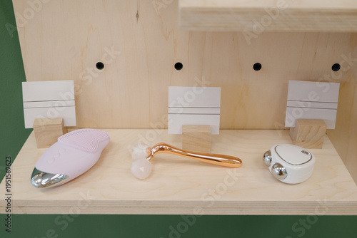 Foto Three facial massagers on a wooden shelf: roller, ultrasonic, mechanical