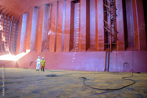 Tableau sur toile crew members in protective suits spray chemical coating on cargo hold bulkhead f